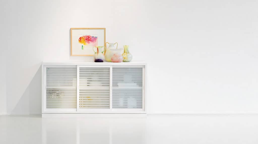 Sideboard „Multimodus 6280-U1“ aus massiver Pinie, weiß lasiert. Mit drei Schiebetüren und Türfüllungen aus Klarglas mit satinierten Streifen.